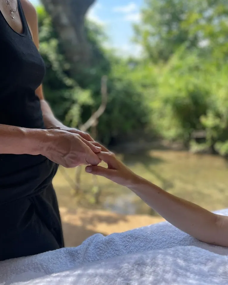 Olivia Marion tenant la main d'une cliente pendant un massage en pleine nature, en Provence